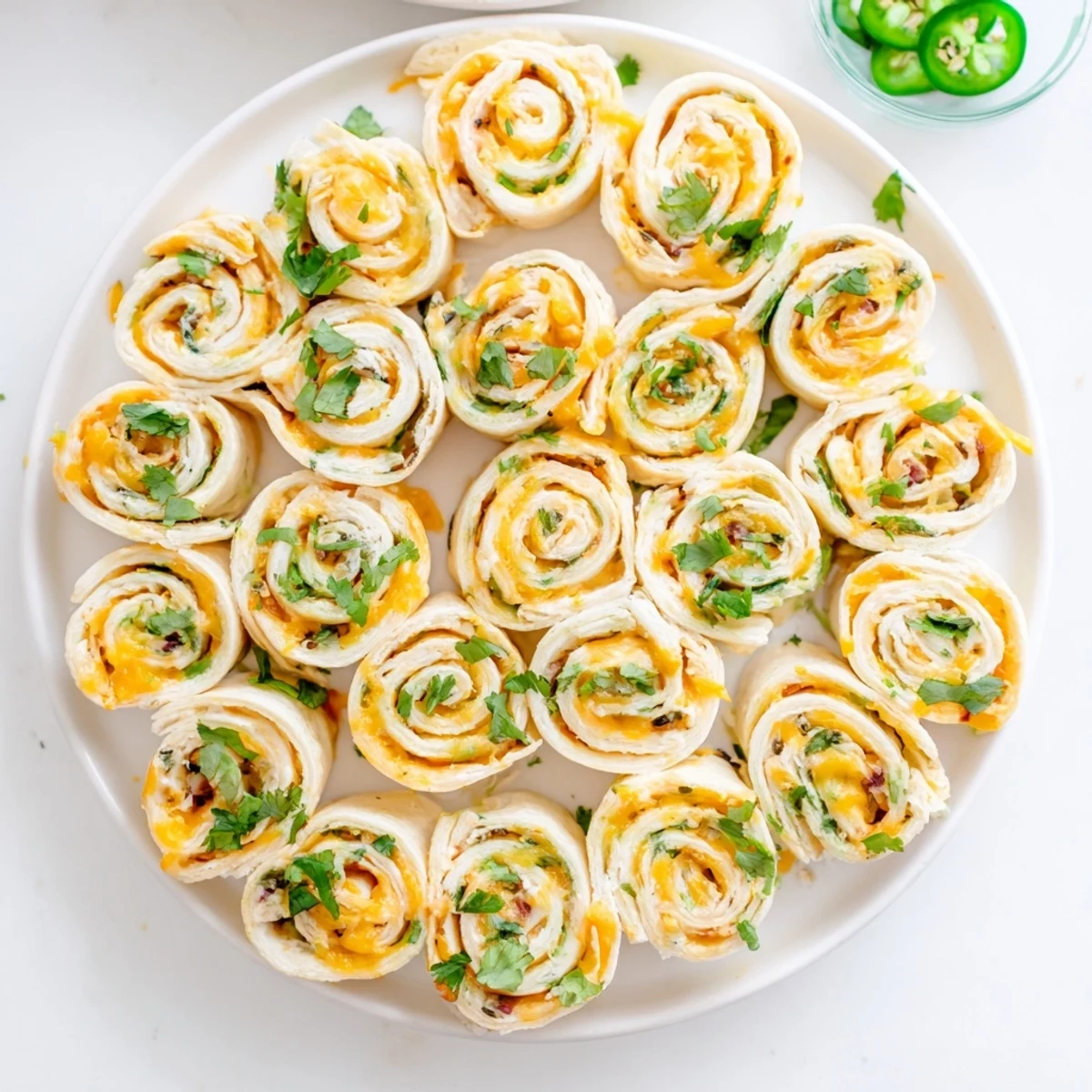 Party platter of easy jalapeno popper pinwheels with golden tortilla edges and melted cheese centers