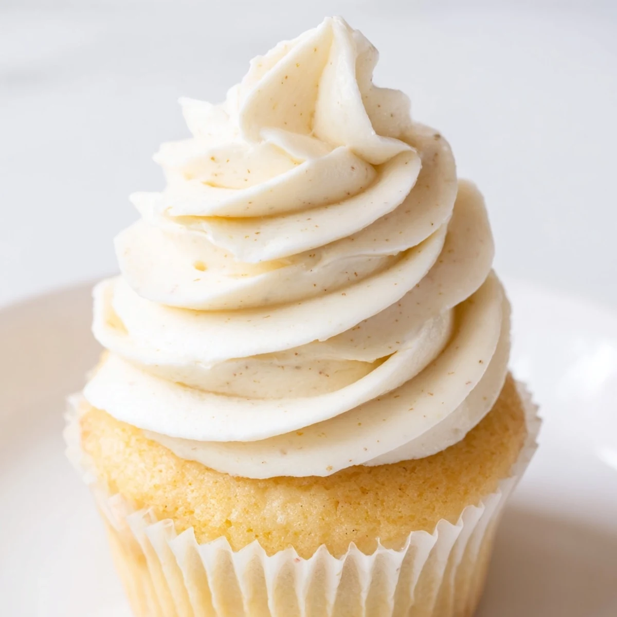 Light and fluffy vanilla cupcakes with tall swirls of vanilla buttercream arranged on a wire cooling rack