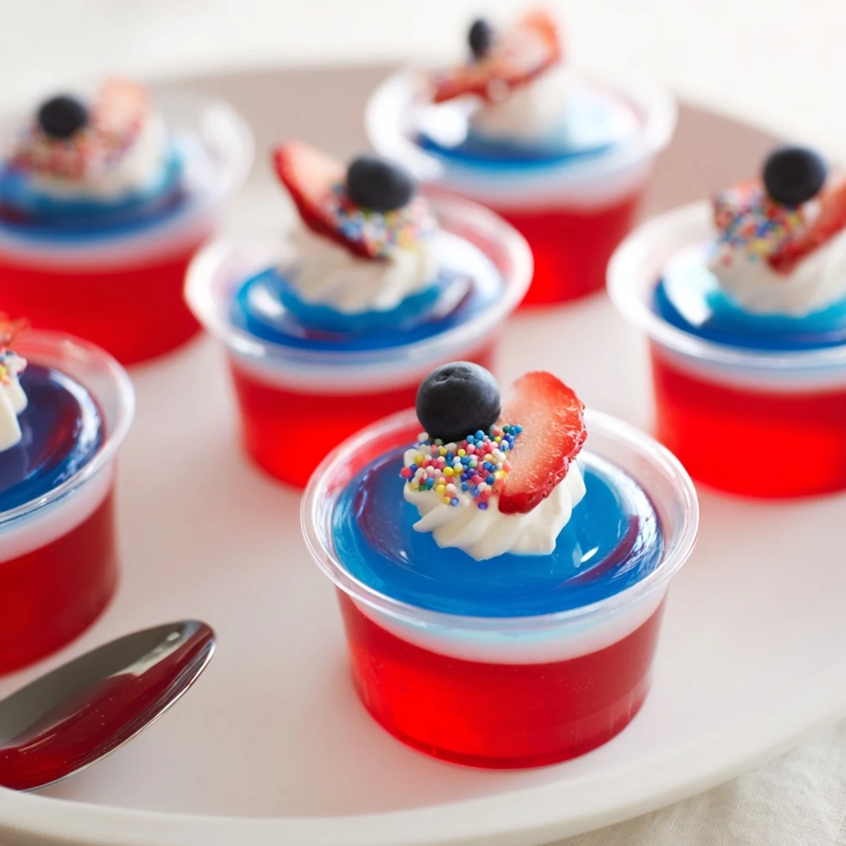 Red White And Blue Jello Cups layered neatly in clear cups, fresh berries