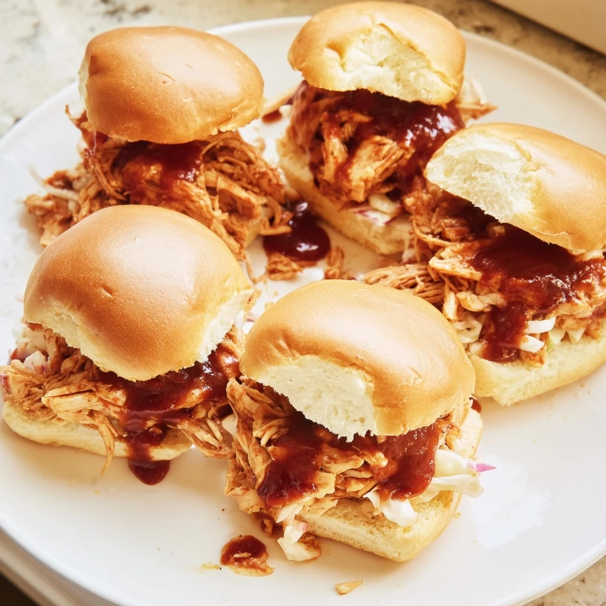 Tangy barbecue chicken sliders loaded onto buttery sweet Hawaiian rolls perfect for gatherings