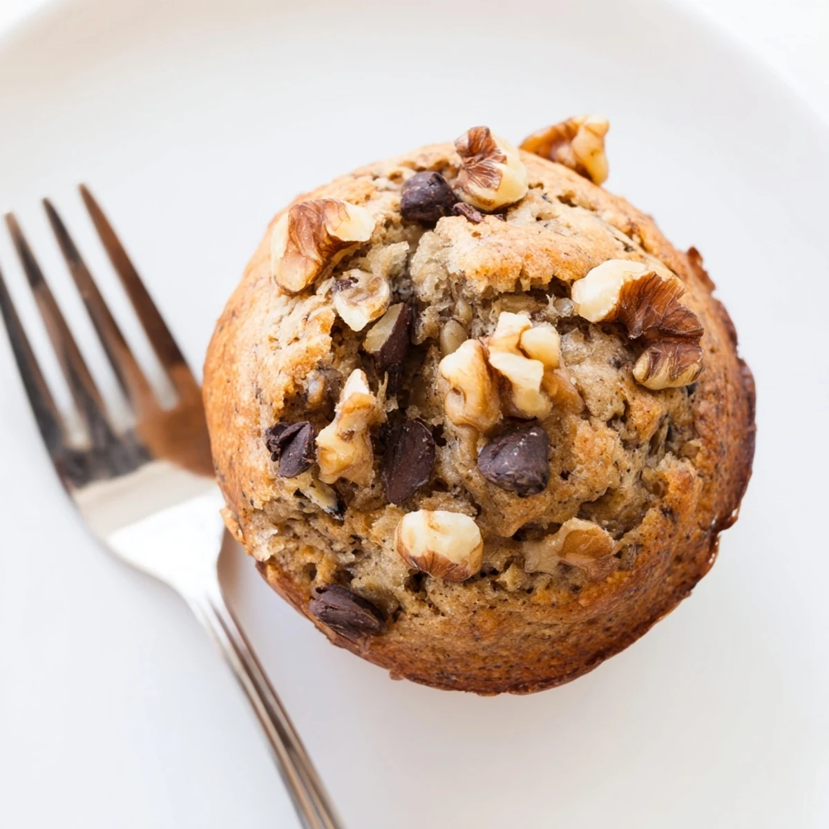 Golden brown healthy banana nut muffins topped with chopped walnuts on a wire cooling rack