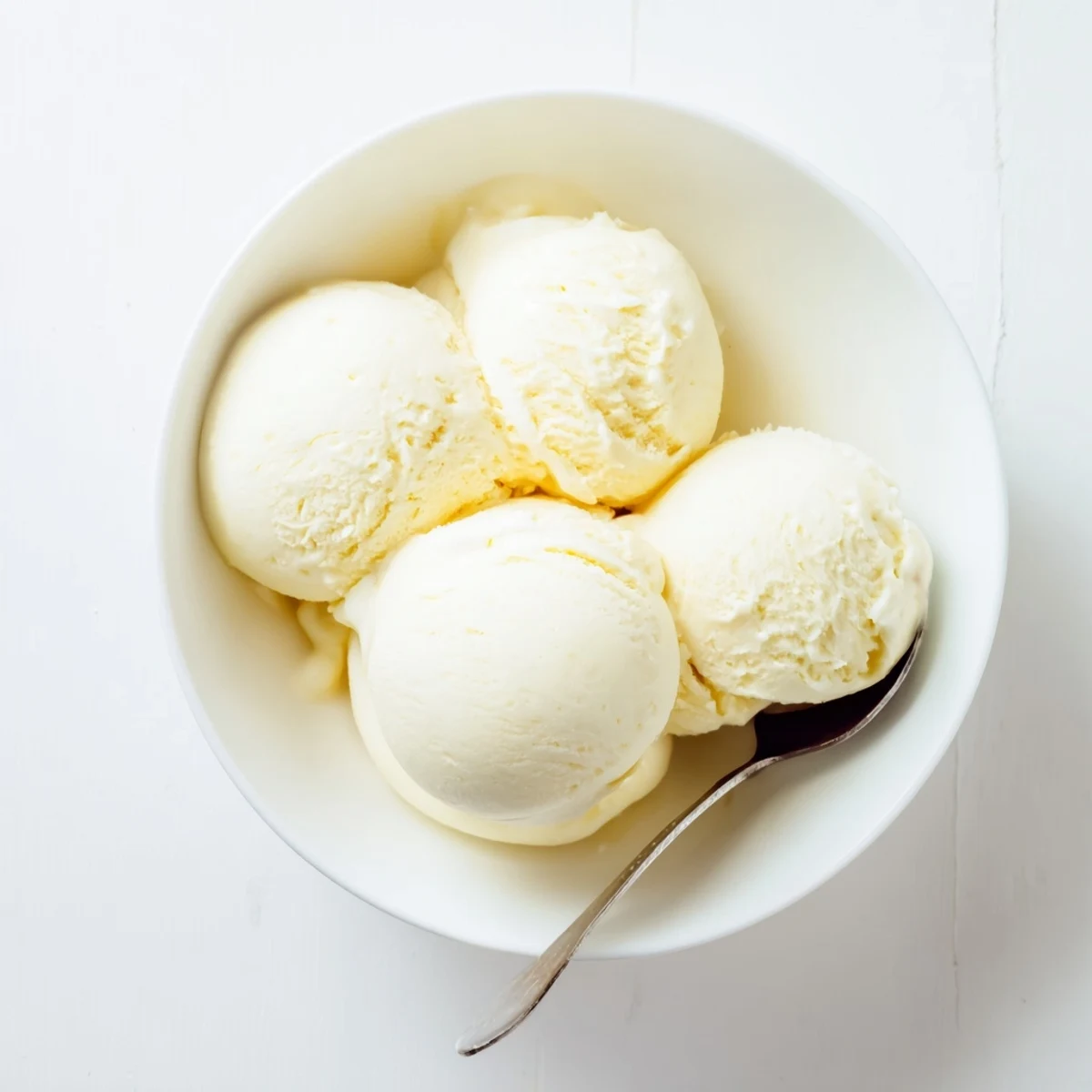 Creamy homemade vanilla ice cream scooped into a chilled glass bowl with garnish
