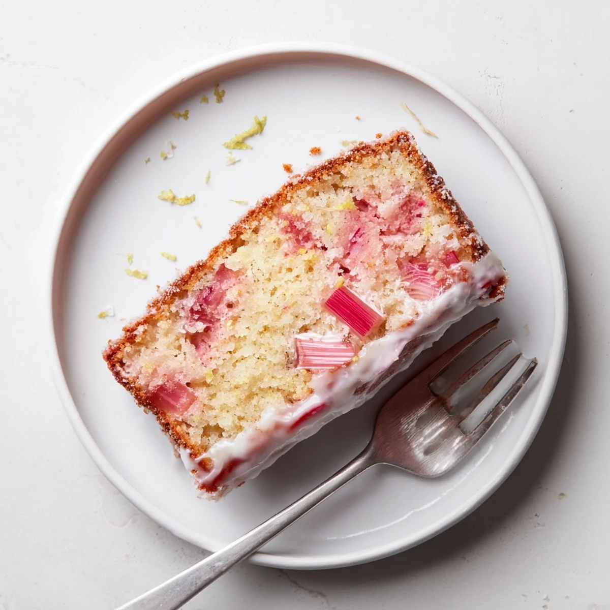 Golden rhubarb lemon drizzle cake with glistening citrus glaze and tender baked fruit pieces