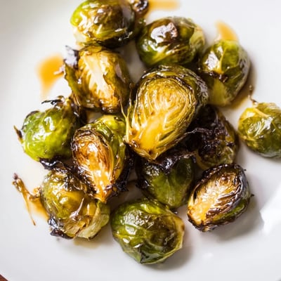 A close-up of crispy Roasted Brussels Sprouts with Balsamic Glaze served on a rustic platter.