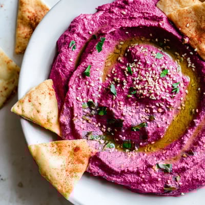 Sliced Roasted Beet Hummus with crispy, golden toasted pita chips served for dipping on a rustic table.