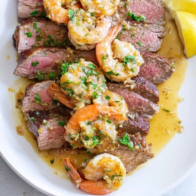Succulent ribeye steak topped with tender garlic butter shrimp and fresh parsley