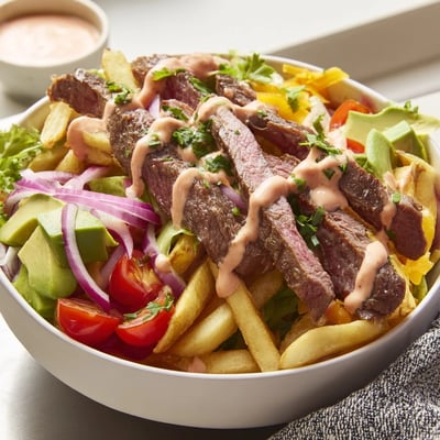 Golden crispy fries cradling seared steak strips drizzled with smoky paprika sauce